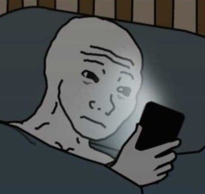Guy in his bed looking at his phone on the verge of tears