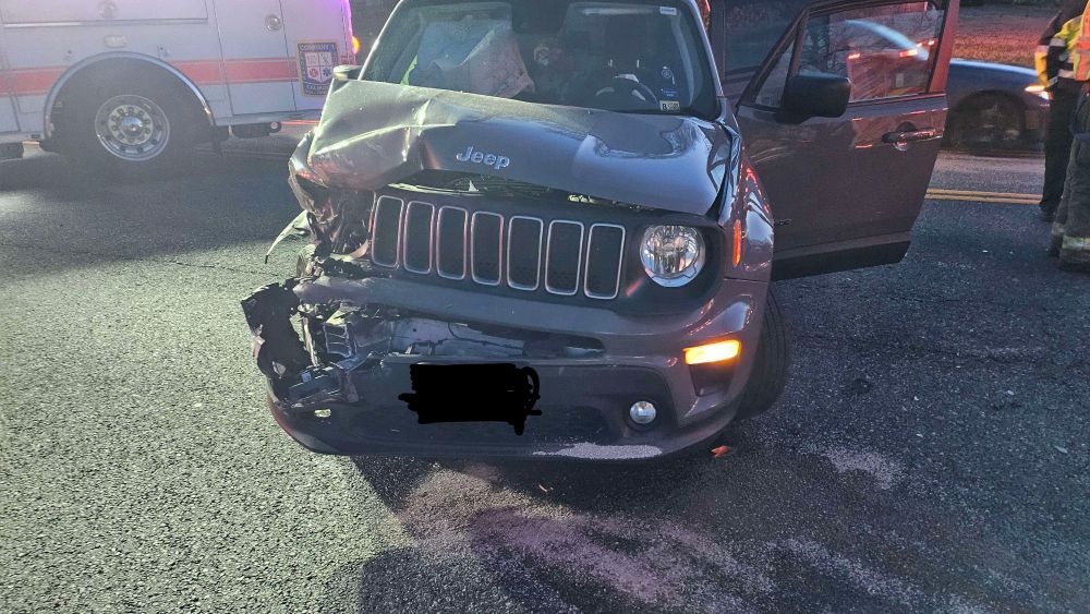 A photo of the dead front of the car, only one headlight working. The left side is extremely bent up, like a monster just took a bite out of the car.