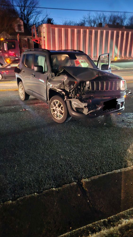 A photo of the front of the car, headlights destroyed, hood bent, and bumper ripped open