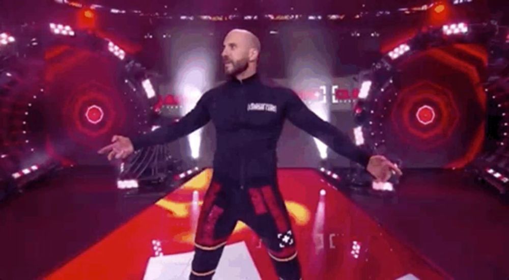 a man is standing on a stage with his arms outstretched in front of a red background .