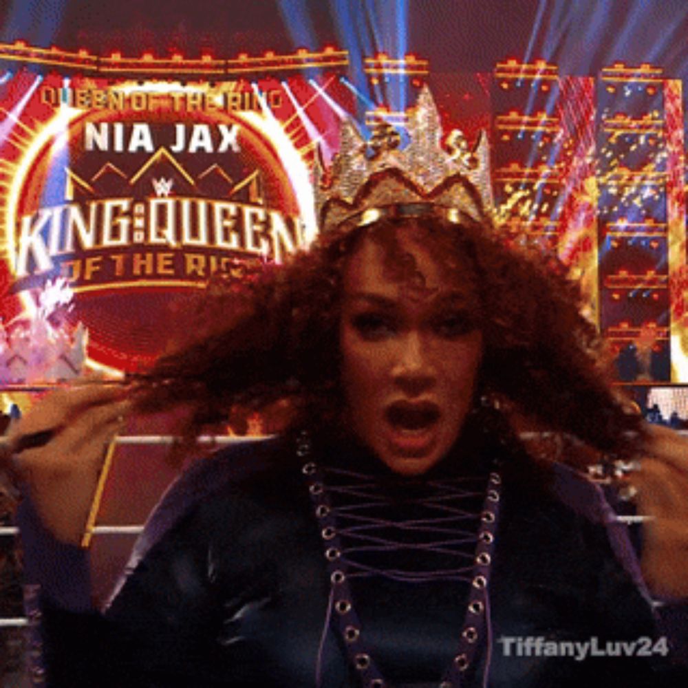 a woman with a crown on her head stands in front of a sign that says queen of the ring