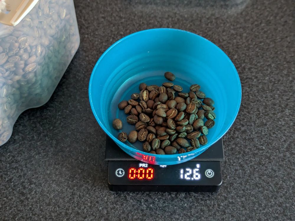 12.6g of coffee beans in a small blue bowl on coffee scales