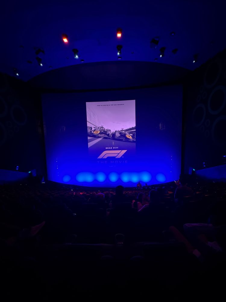 Movie theatre screen with a poster of the F1 movie projected onto it. 