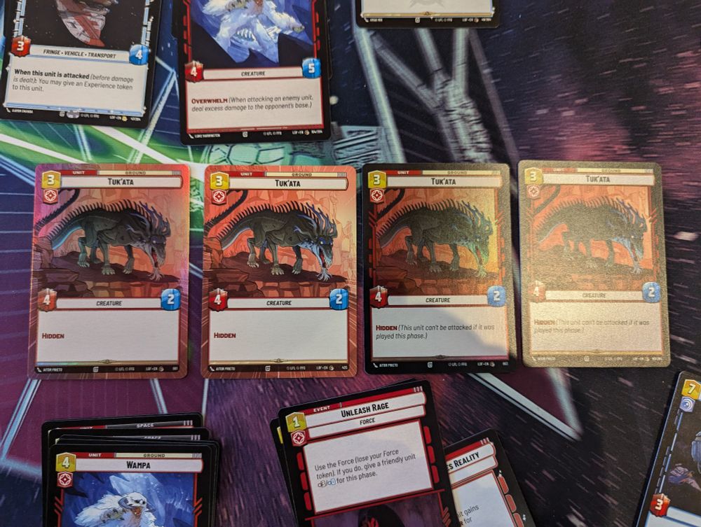 Four copies of the card Tuk'Ata from the Legends of the Force set of Star Wars Unlimited.  One is the normal card, one is a foil card, one is a Hyperspace card, and one is a Hyperspace Foil.