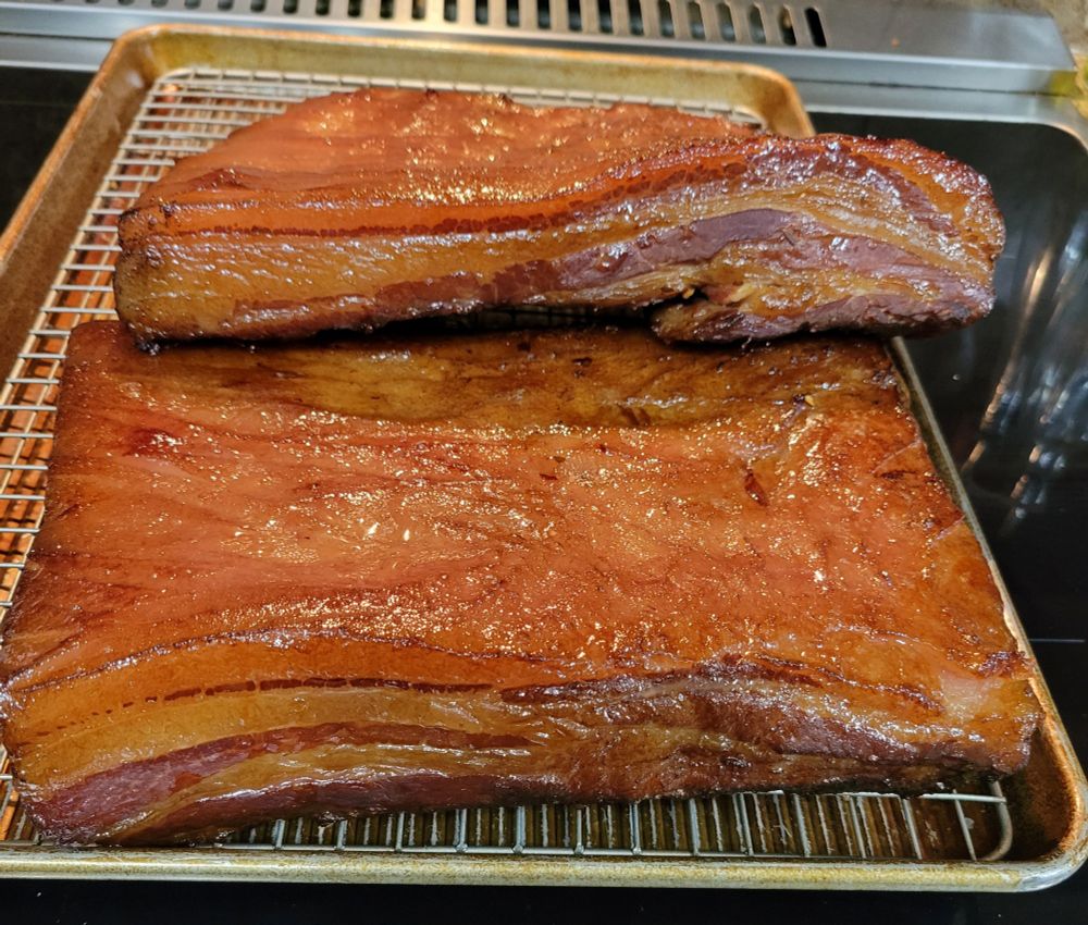 Finished pork belly (bacon) sitting on a pan hot off the smoker.