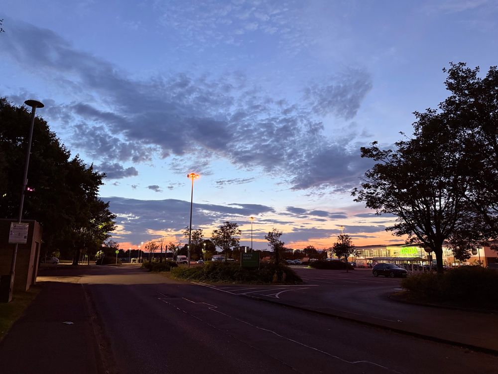 A striking sky with wispy grey clouds and the last remnants of a fiery sunset peeking in from the bottom. If you look closely you can see that this beautiful scene is above the Asda Govan car park.