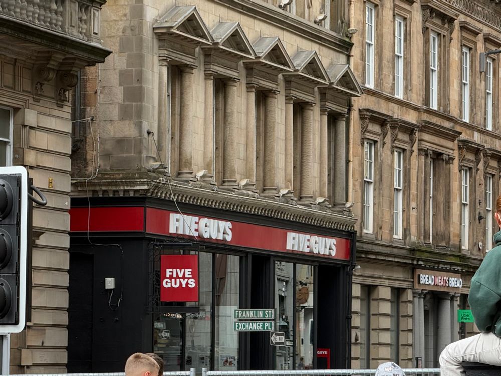 The Five Guys on Glasgow’s St Vincent Street now has a US-style street sign outside it, which says “Franklin St” and “Exchange Pl” above a One Way arrow sign. They’ve not made any attempts to cover up the Bread Meats Bread sign next door.