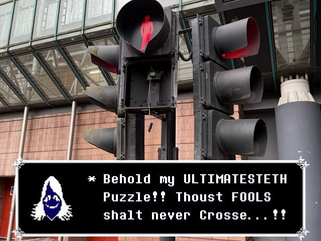 A photo of a traffic light where the green ‘walk’ signal has been entirely removed. Overlaid is dialogue from Rouxls Kaard saying “Behold my ULTIMATESTETH Puzzle!! Thoust FOOLS shalt never Crosse…!!"