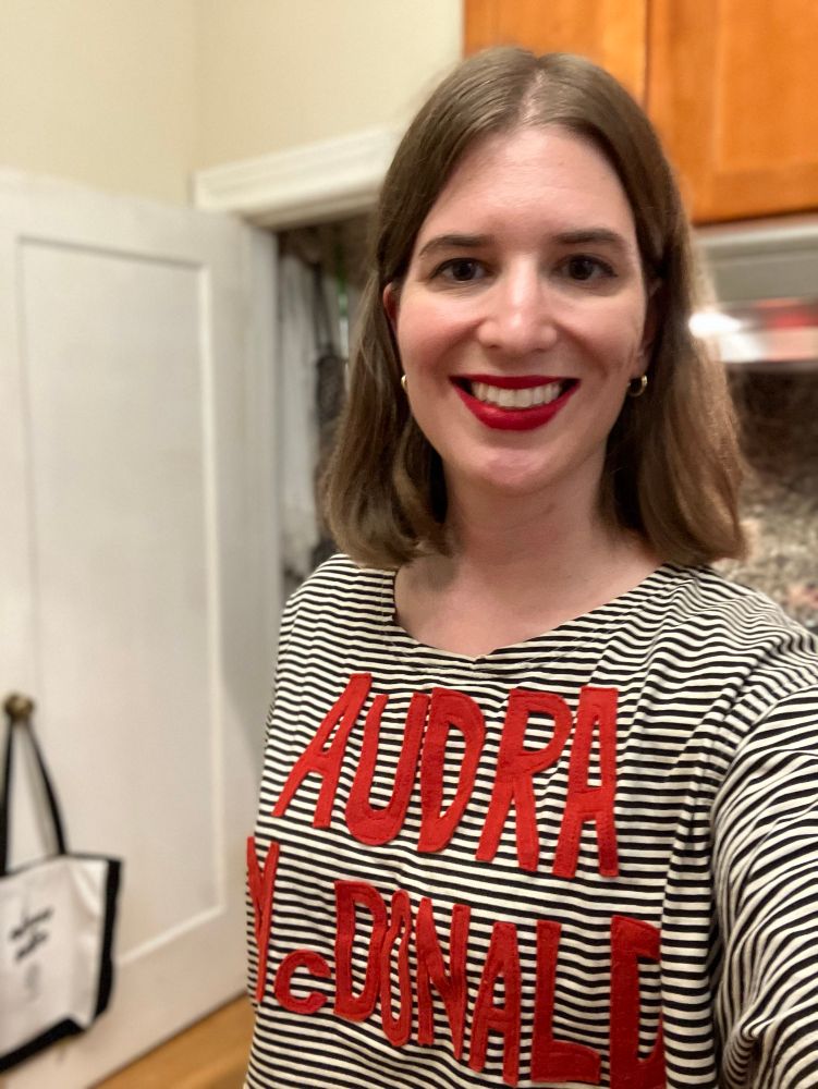 Selfie of a white woman in her 30s, wearing a black-and-white-striped T-shirt with “AUDRA McDONALD” appliquéd on it in red felt 