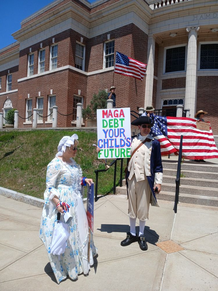 Man and woman dress in ye old style clothes, protesting. 