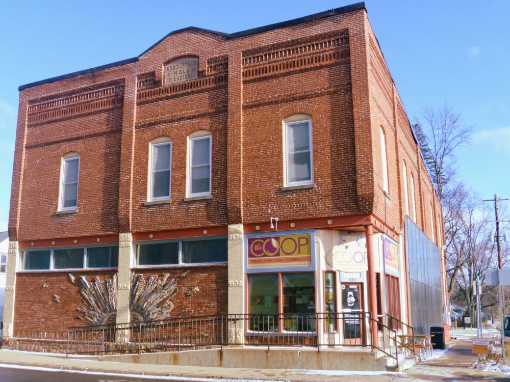 Photo of an older brick building with a stonework mural on its front.