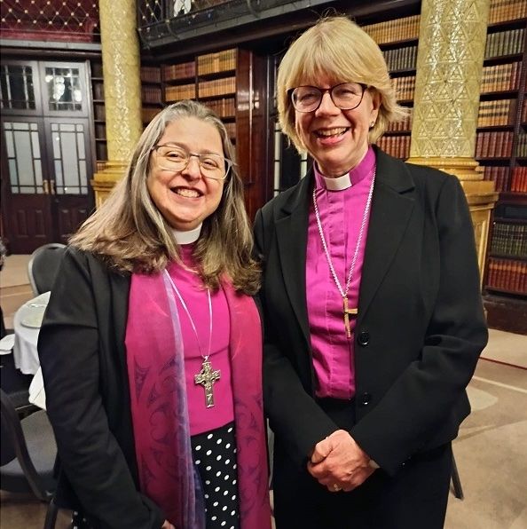duas mulheres brancas de indumentária vermelha cardinal sorriem para a câmera