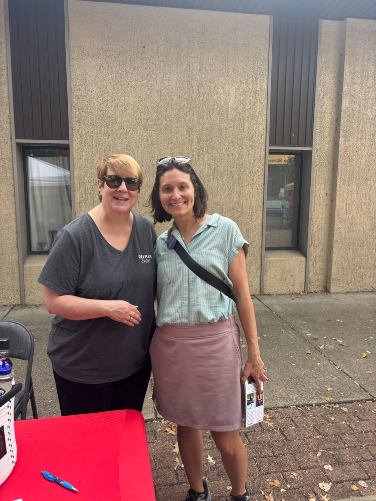 Lissa and an Aspinwall Council candidate smiling on a sidewalk on Commercial Ave. with the side of a building visible behind them.