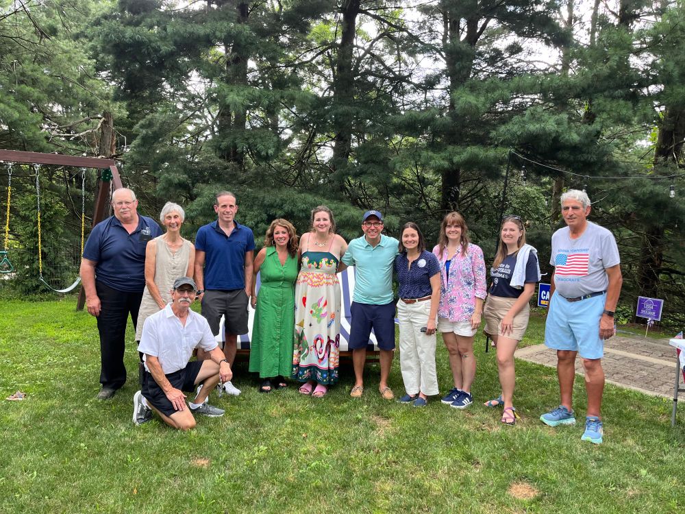 Group of people smiling at the camera including Lissa, and candidates for court of common pleas. trees and a swingset are visible behind a group of 10+ individuals. 