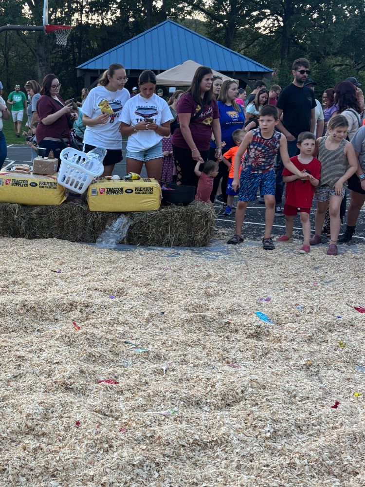 Three children lined up in front of a hay scavenger hunt.