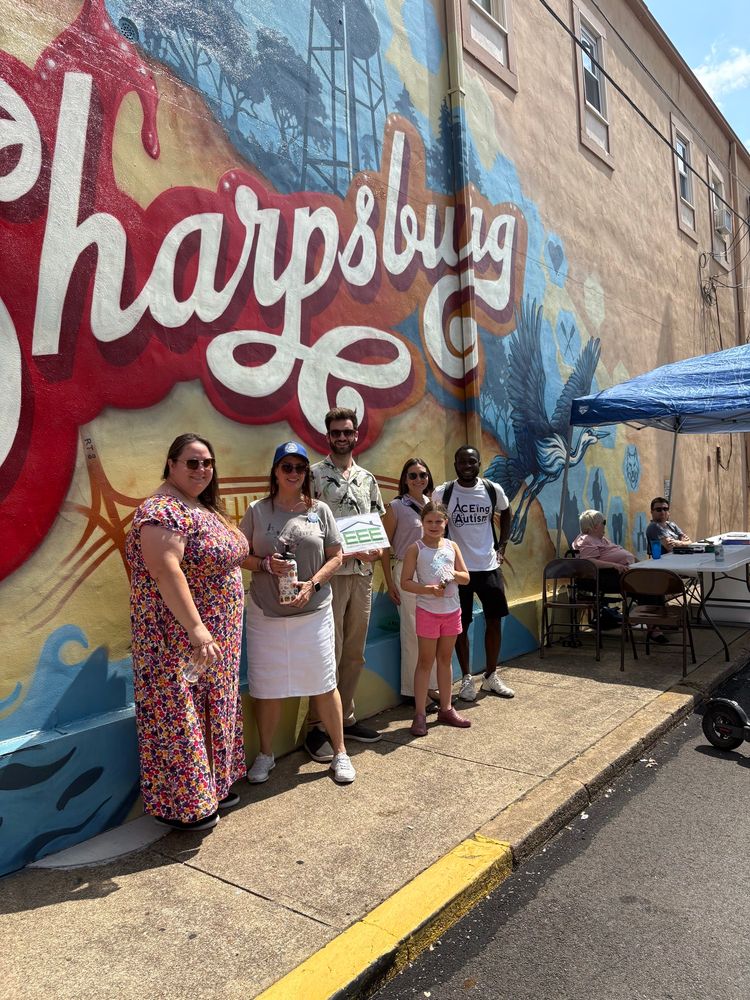 Photo of Lissa and a group of people under the Sharpsburg mural.
