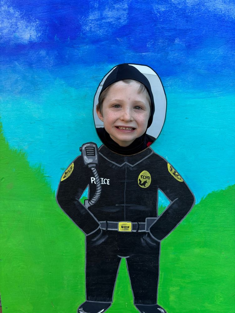 Young boys head peeking through a photo cutout that dresses him as a Fox Chapel police officer.