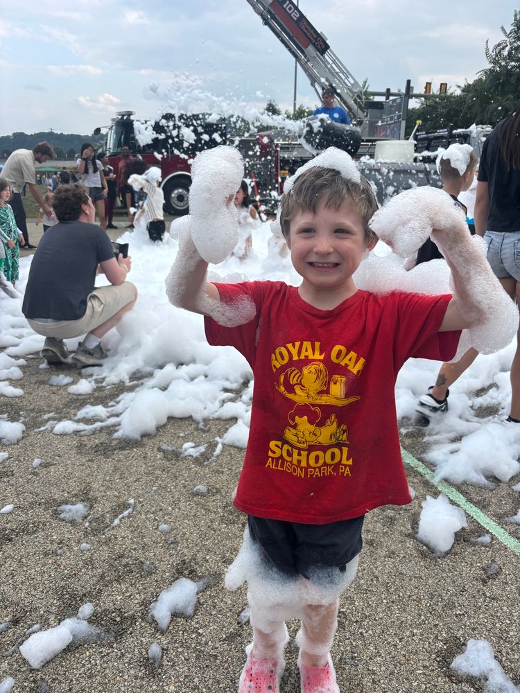Child smiling at camera covered in bubbles