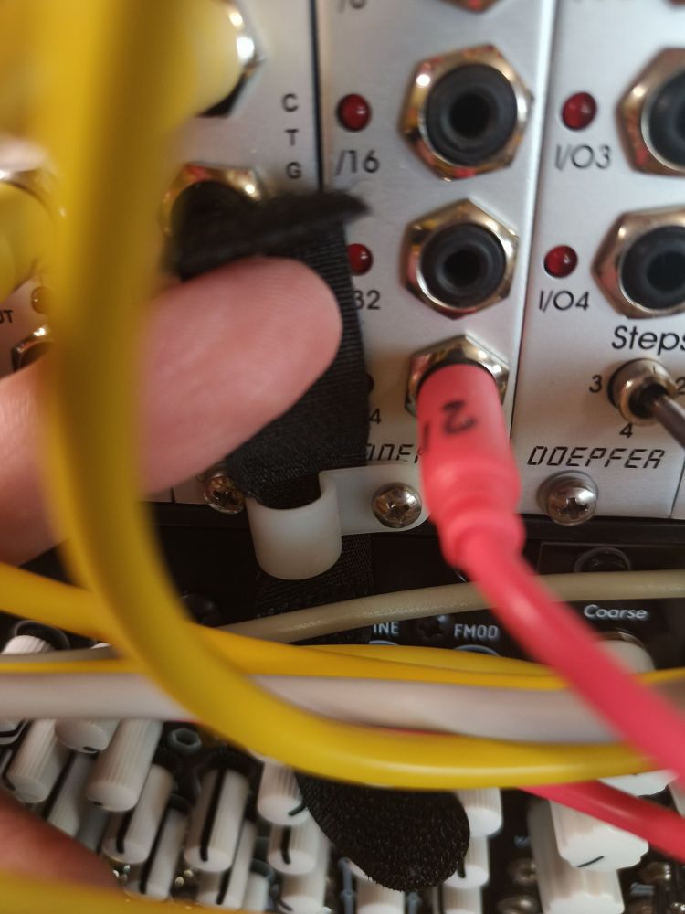 A small velcro tie going through a plastic cable wall mount thingy