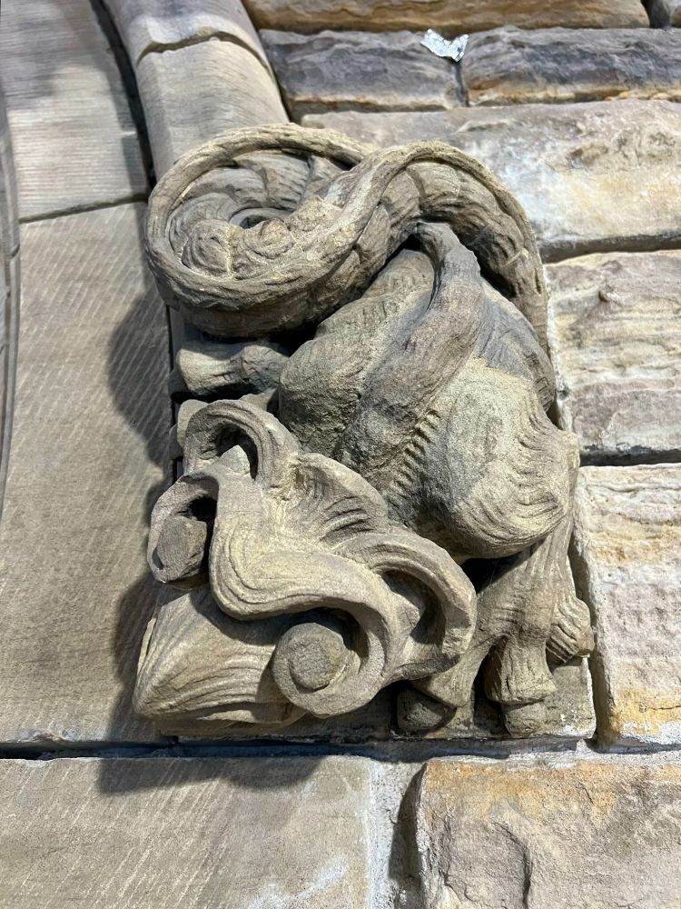 sandstone label stop carved as a lizard-like creepy crawly
