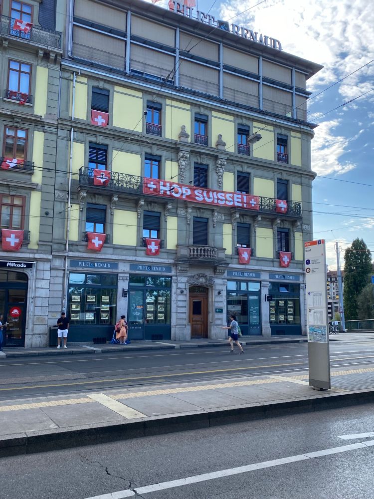 A building in Geneva with Swiss flags and a banner saying “Hop Suisse”