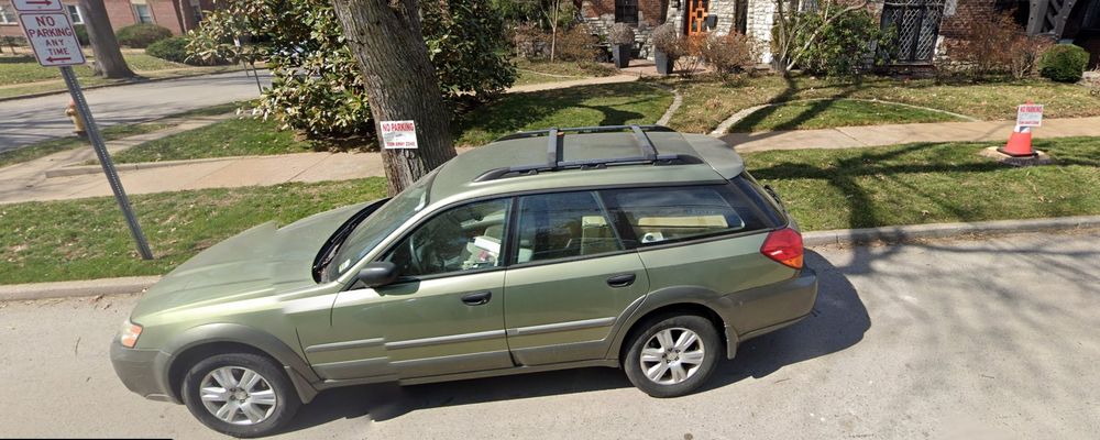 green subaru outback parked around numerous no parking signs that has been taken away to i don't know who cares 