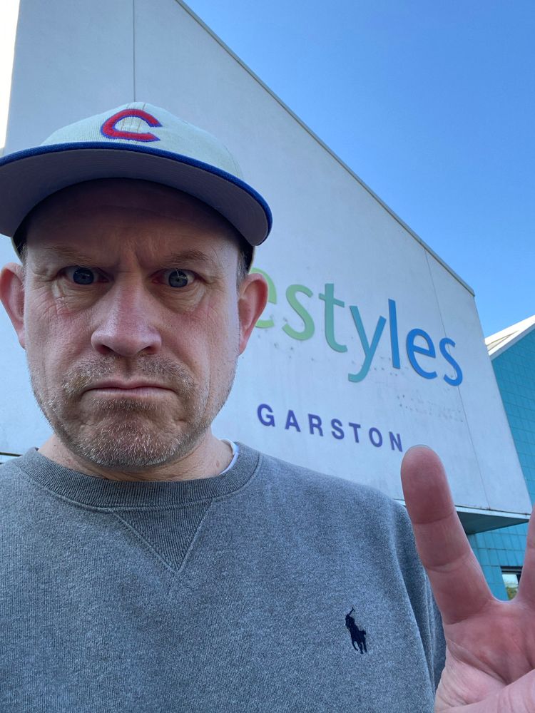 A man with a cap on hoisting the peace sign