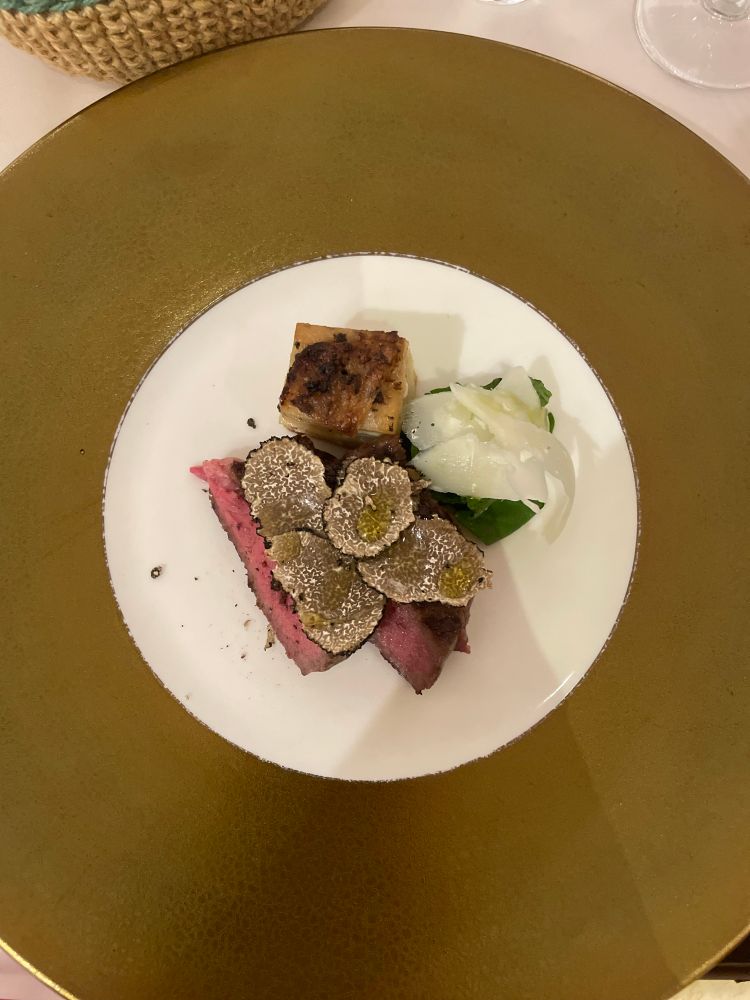 和牛の赤身レアステーキとサマートリュフが金縁の大皿に盛り付けられている