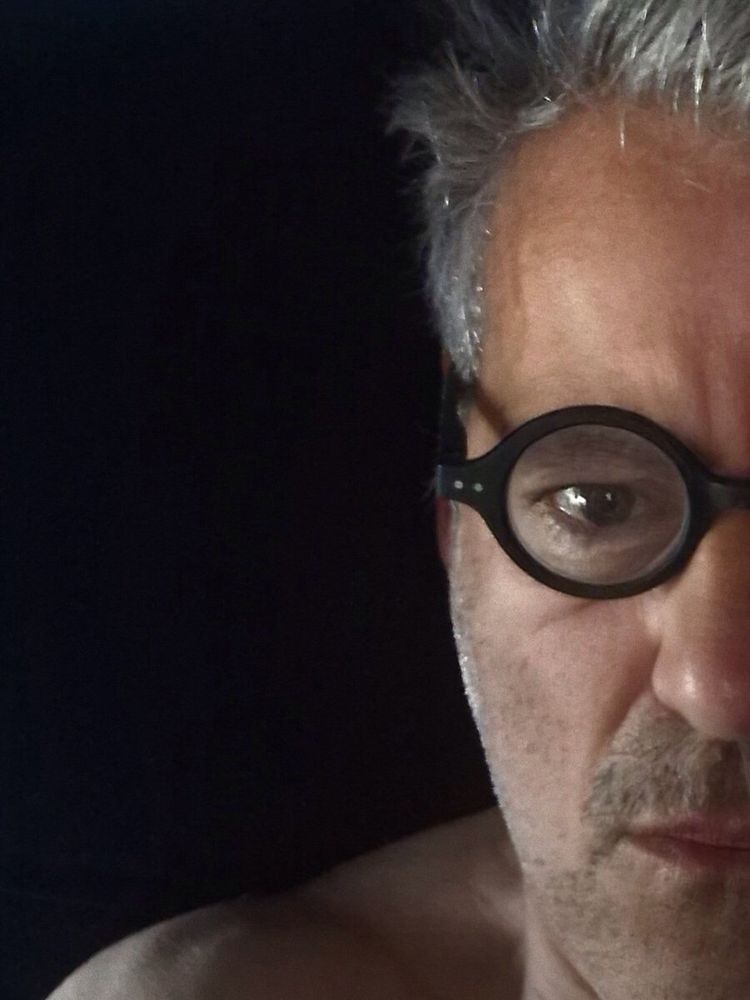 Gorgeous picture of Rupert, black, round glasses, and a hint of shoulder (bare).