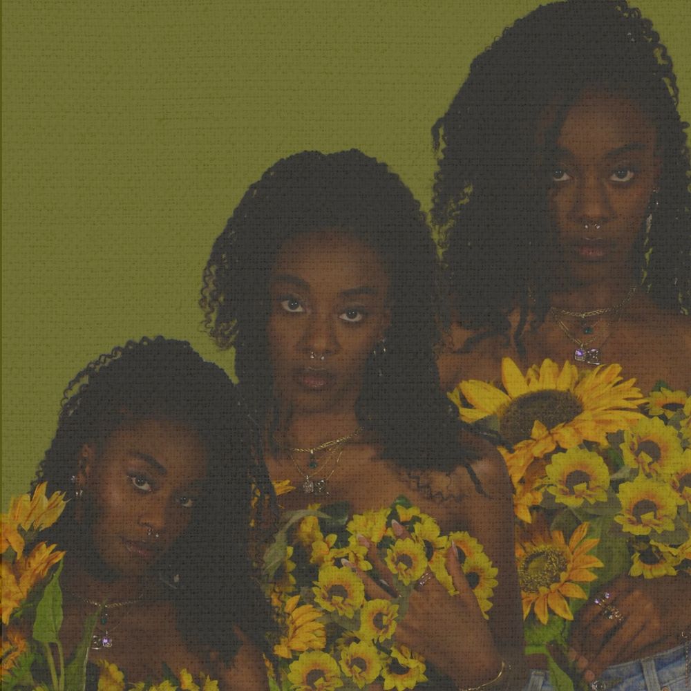 Green background, black girl holding sunflowers, wearing a strapless top made of sunflowers and jeans