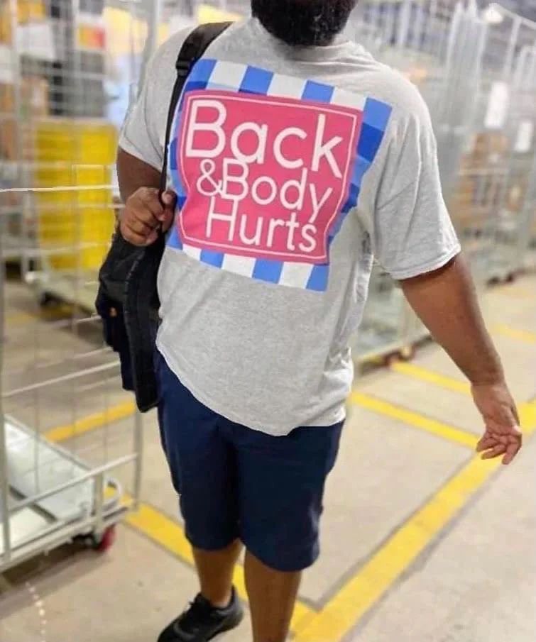 Man wearing a grey t shirt that says “Back and Body Hurts” that us stylized like the “Bath and Bodyworks” logo with a pink square and blue and white checker border. 