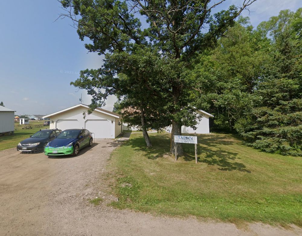 The corporate headquarters of Talon Metals, a publicly traded company on the Toronto Stock Exchange, appears to be a small house on a dirt road with two cars parked in front of the garage. A sign in the yard says "Talon Metals".