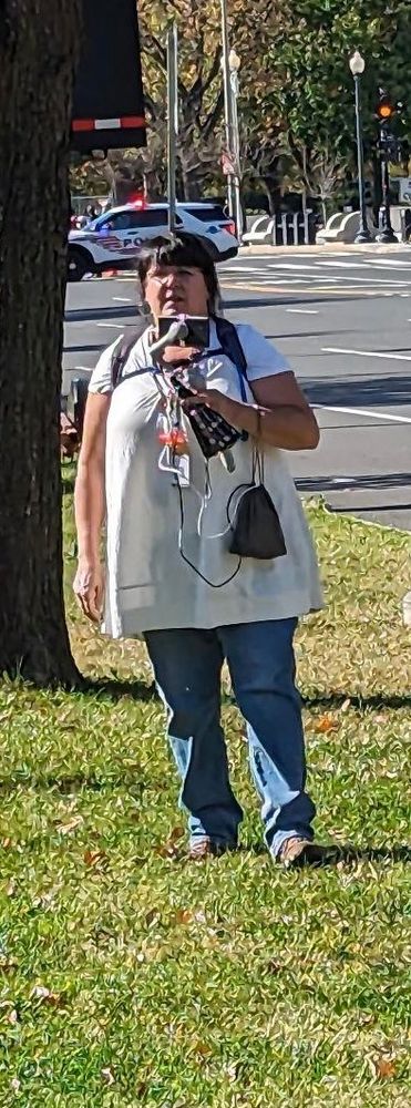 ID: photo of Glorybee - fake press, real fascist J6er, wearing a bagging white shirt, blue jeans, and a phone on a gimbal.