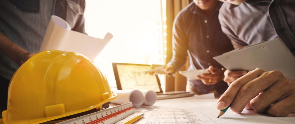 a yellow hard hat on a table surrounded by blueprints