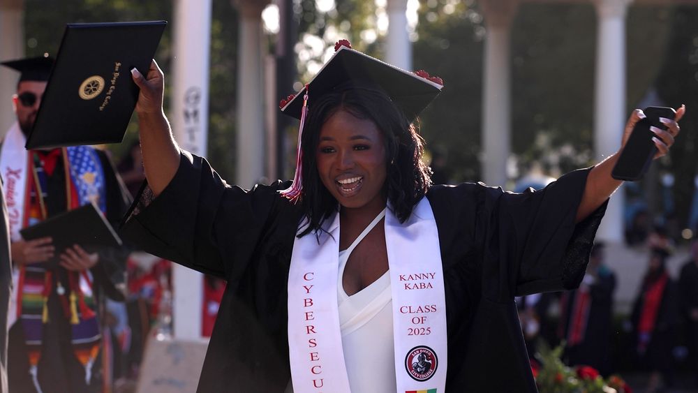 A student celebrates on stage as she receives her diploma at City College's Commencement
