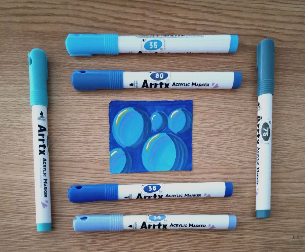 Picture of a small drawing of big bubbles drawn with a set of blue and teal Arrtx markers arranged around the small drawing
