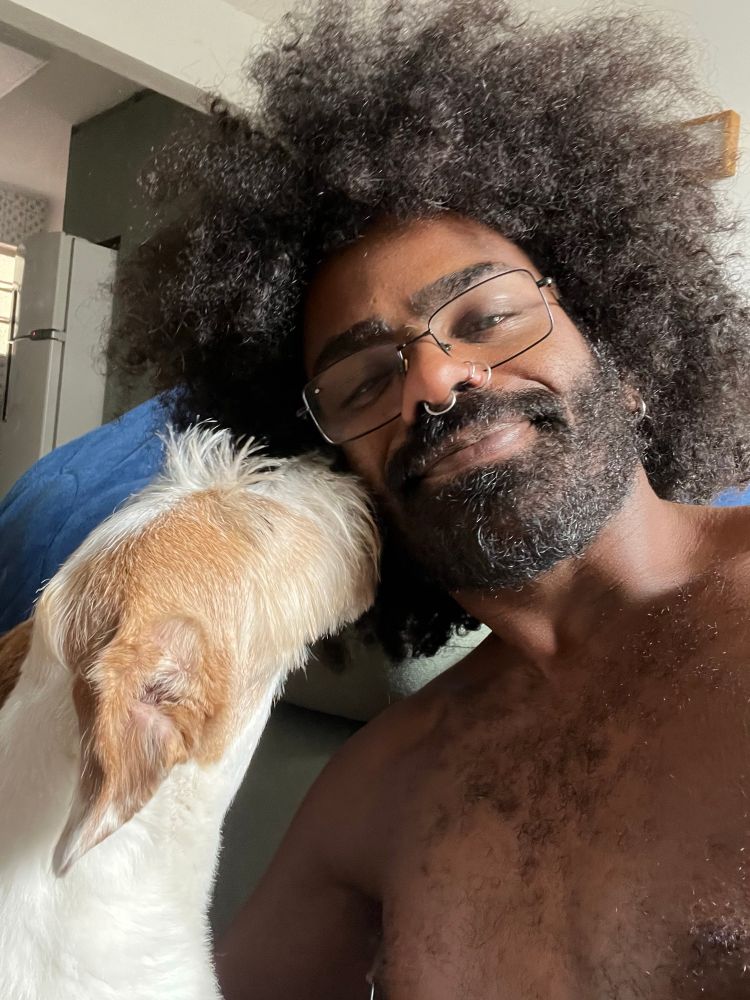 eu e uma cachorra juntos. eu sou um homem preto de barba grande e cabelo black power ela uma cachorra branca com as orelhas caramelo 