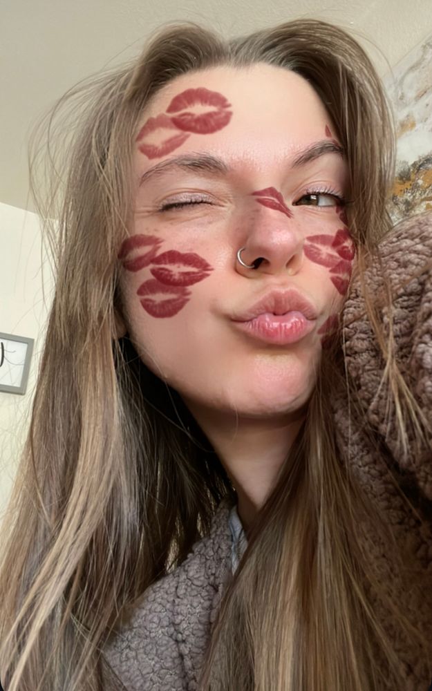 selfie of a white brunette girl making a kissy face while winking, with a kissy lip filter on her face