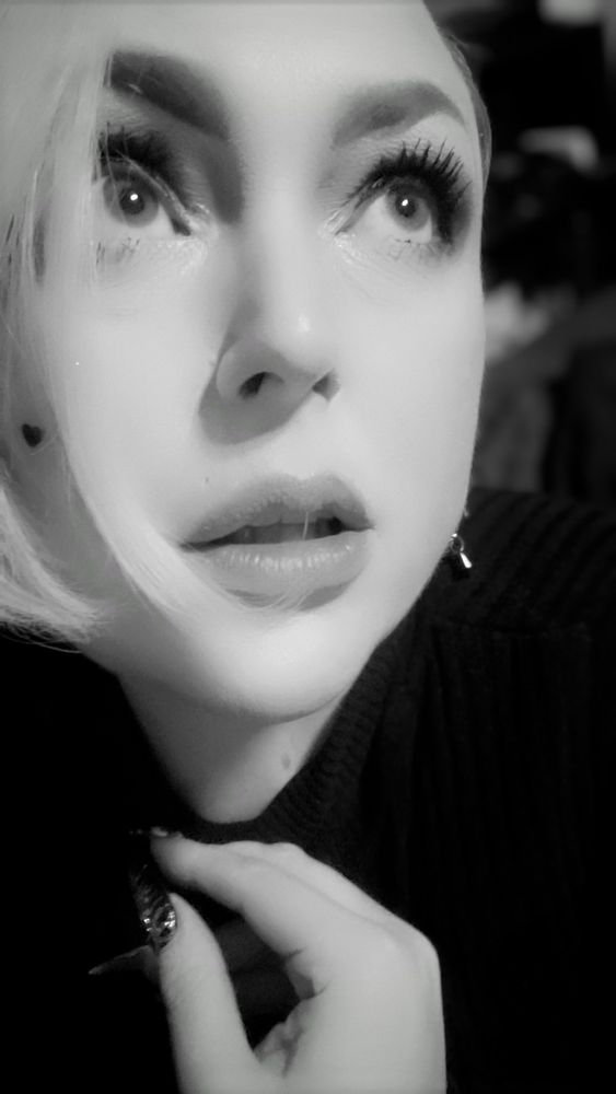 Black & white photo of pretty woman in black turtleneck with blonde hair looking upward 
