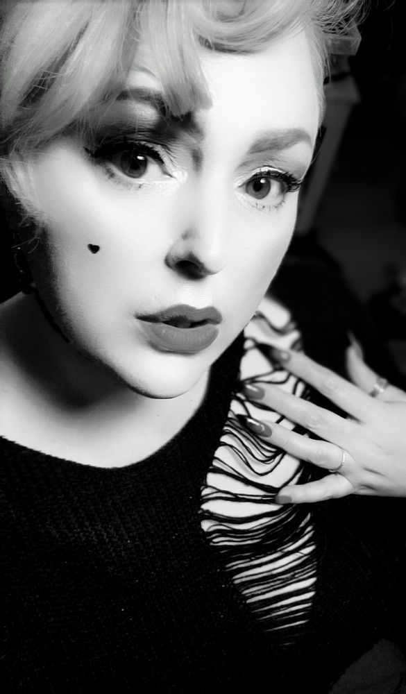 Pretty, movie star-esque woman with curled hair and a ripped sweater. Photo in black and white. 