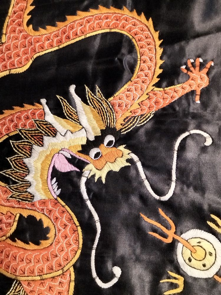 'Goldener' chinesischer Drache als Stickerei auf schwarzer Seide.
