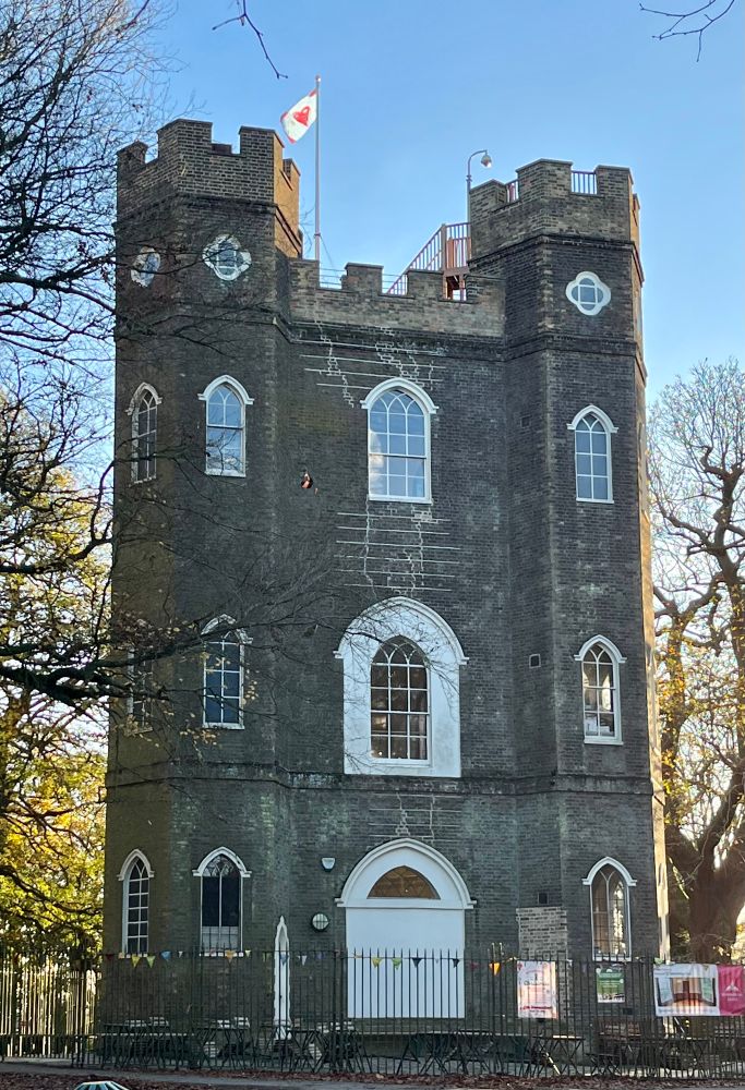 A gothic folly in the middle of woodlands, flying a flag from the roof. The flag is a drawing of the building in the middle of a heart shape