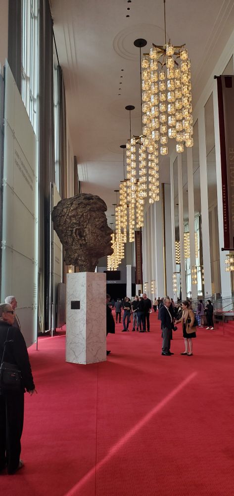 Busy of president Kennedy and rows of chandeliers, red carpet