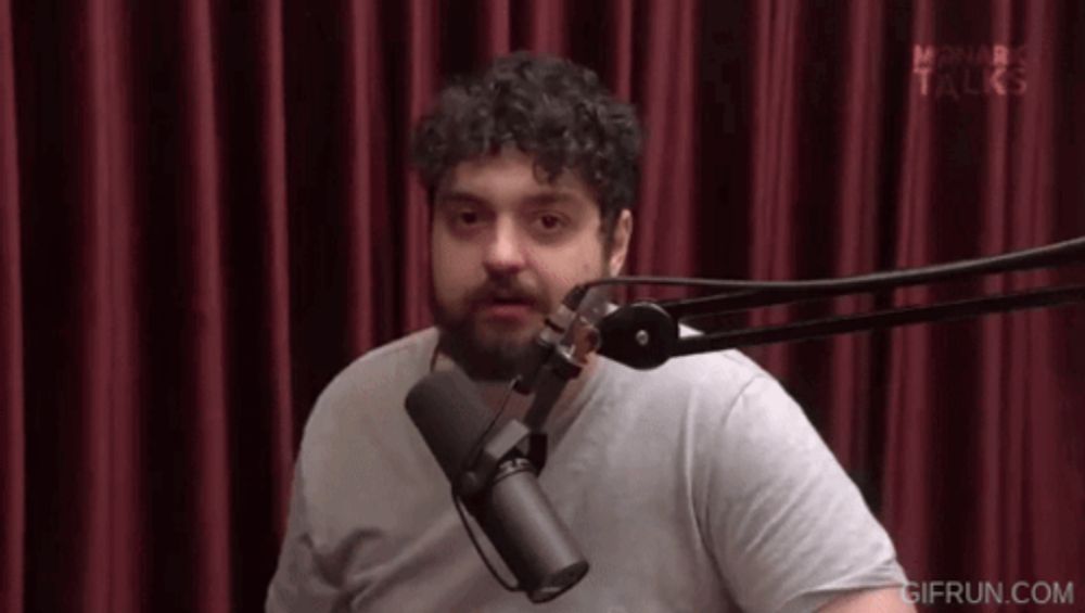 a man with a beard is sitting in front of a microphone in a studio .