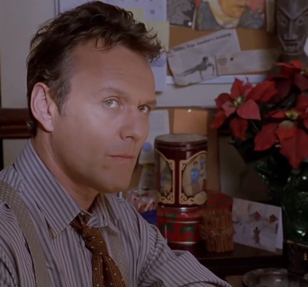 A screenshot from the Buffy the Vampire Slayer episode “Amends” showing Giles sitting at his house with a specific Christmas cookie canister in the background