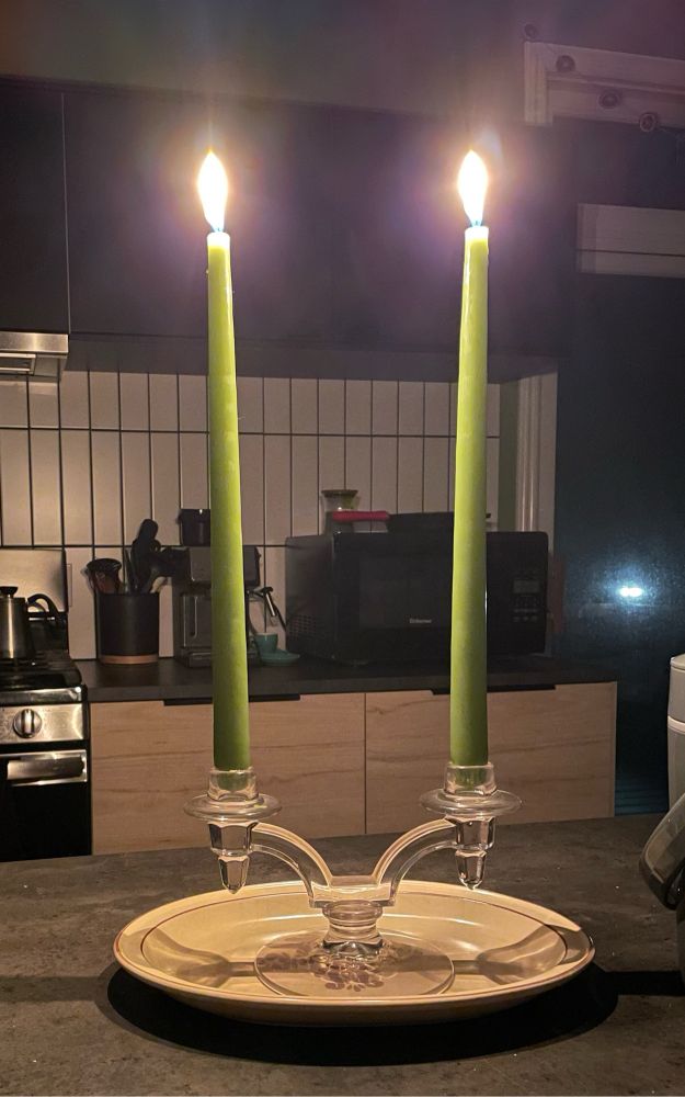 A photo of two lit green candlesticks. They look pretty, but it’s also a bummer.