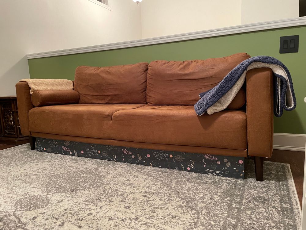 A photo of the same couch and box, but now the box is covered with floral contact paper to make it seem even a little bit intentional