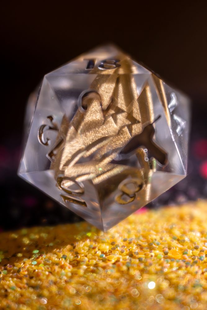A close up of a translucent twenty-sided die, illuminated by the side and behind to reveal a golden Starfleet insignia suspended inside.
