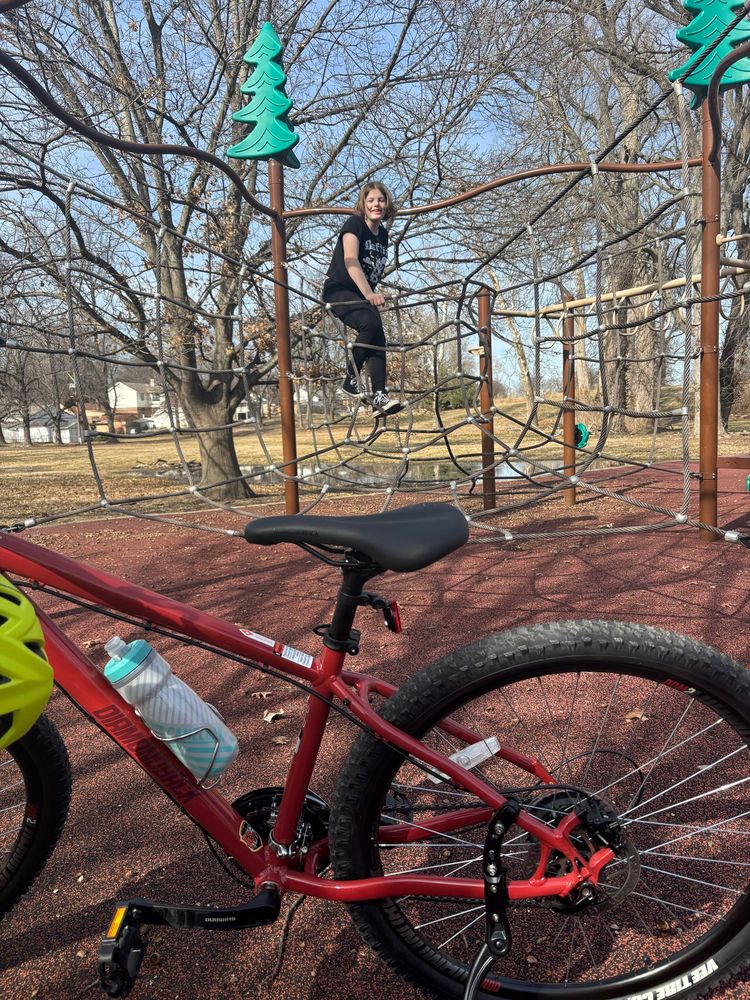 Max taking a playground break, their bike in the foreground 