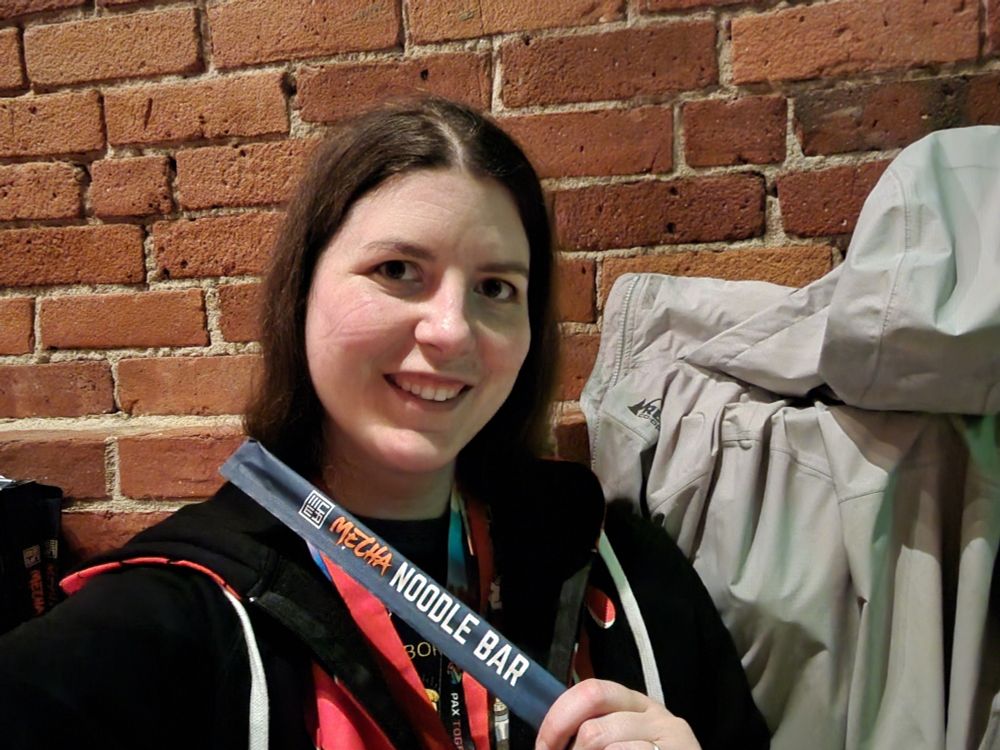 Me in front of a brick wall holding Mecha Noodle Bar branded chop sticks